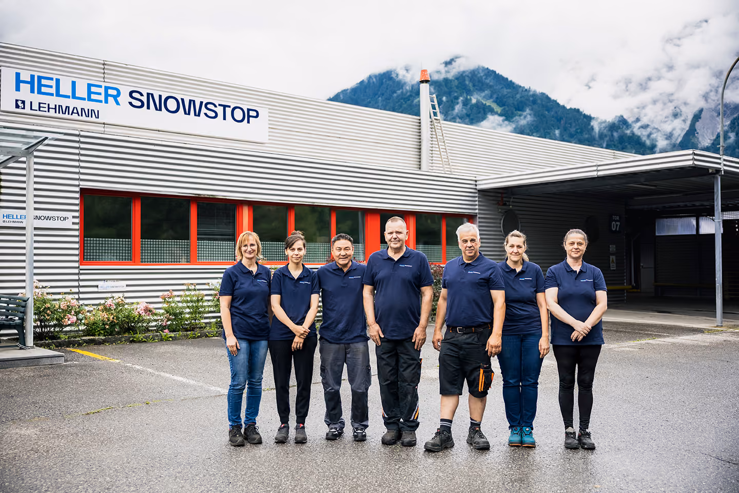 Industrieroboterarm steuert eine Maschine in einer Fabrik, während eine Person einen Bedienpult hält.