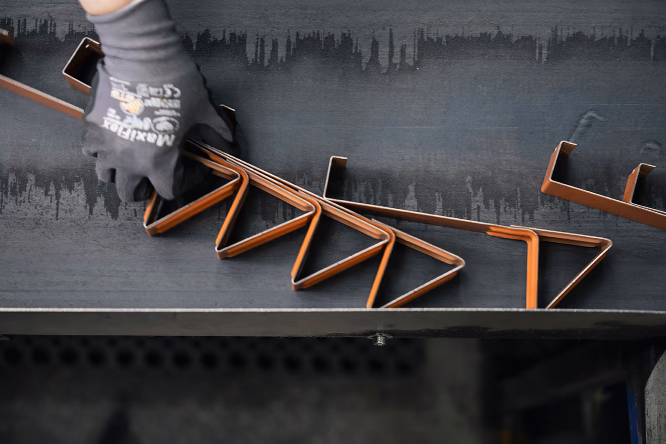 Mehrere Metallteile hängen in einer Produktionsanlage zur Oberflächenbehandlung.