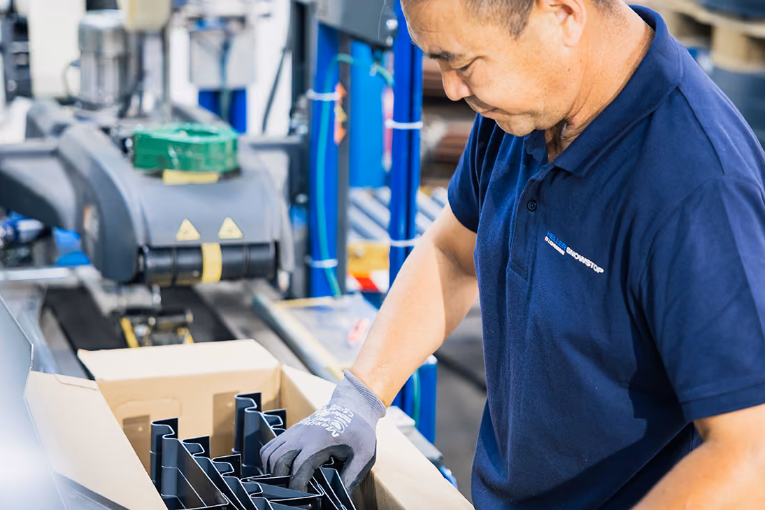 Mehrere Metallteile hängen in einer Produktionsanlage zur Oberflächenbehandlung.