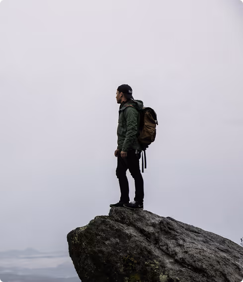 Hiker standing on rocky cliff with backpack