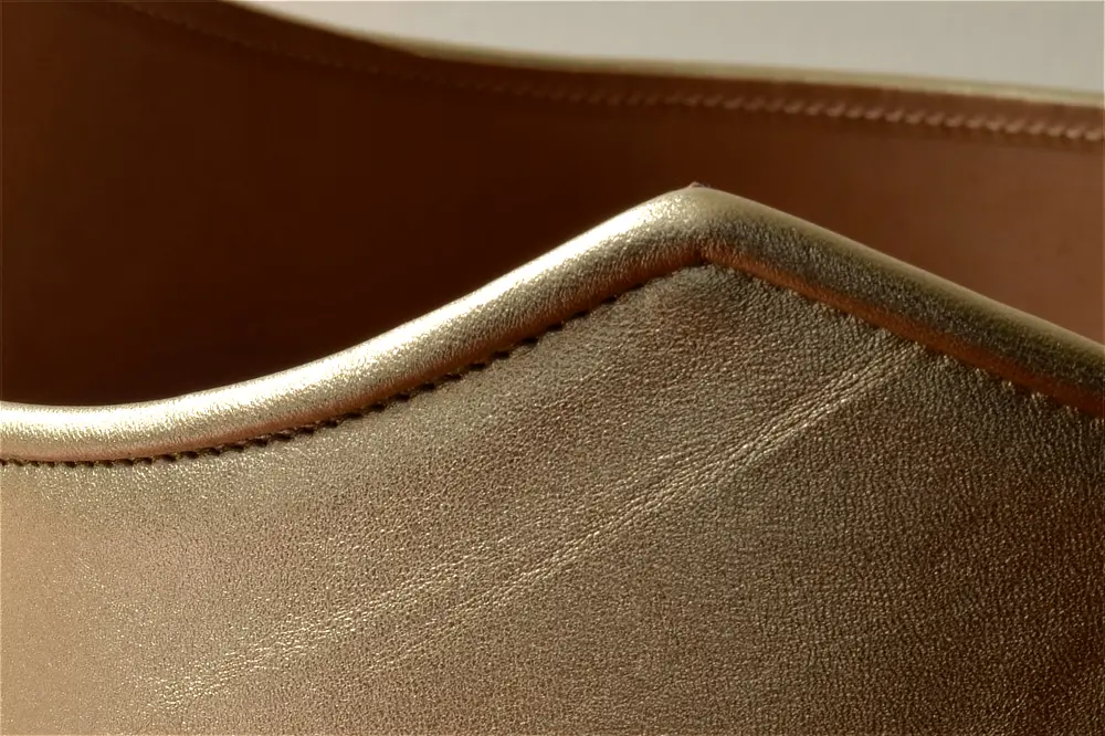 Close up of a sculptural leather belt showing the binding round the edges