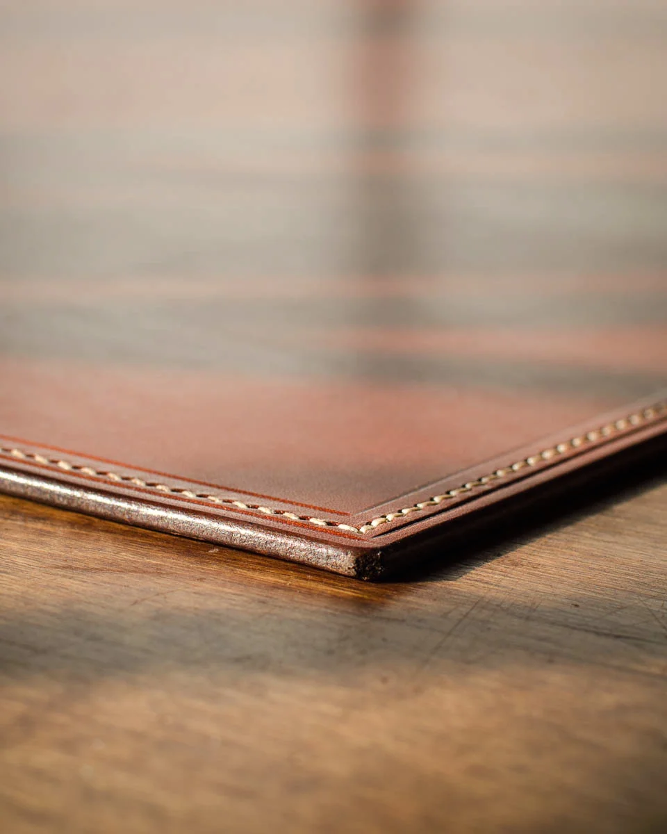 a detail shot of the corner of a leather desk mat for a hotel. It shows the edge finishing and stitching.
