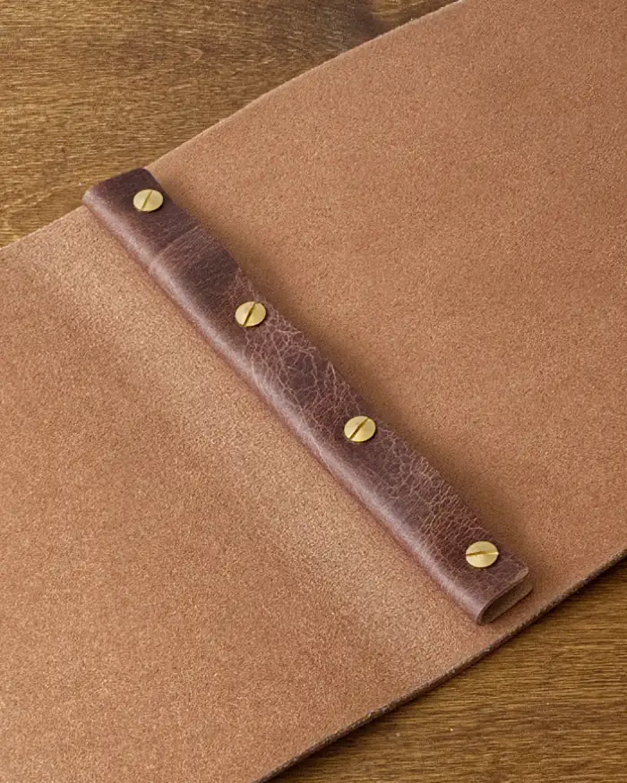 Detail shot of a heavy leather menu showing the binding posts and retainer to keep the pages located.