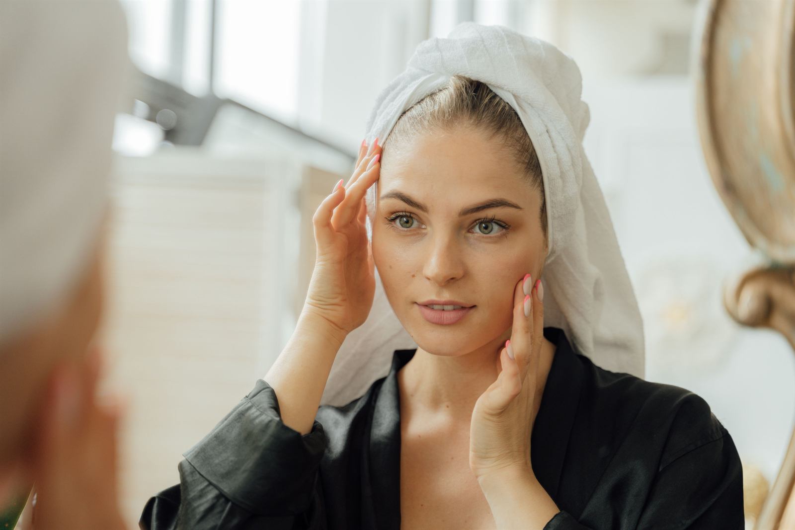 Woman examining facial volume loss in the mirror after significant weight loss