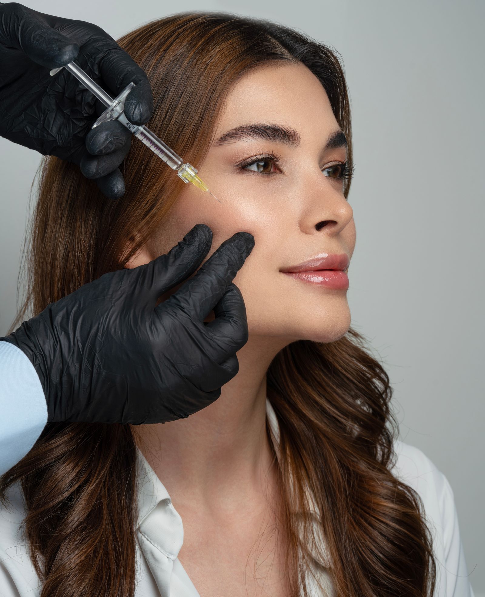 Practitioner assessing a patient's cheek and temple area during a facial volume restoration consultation