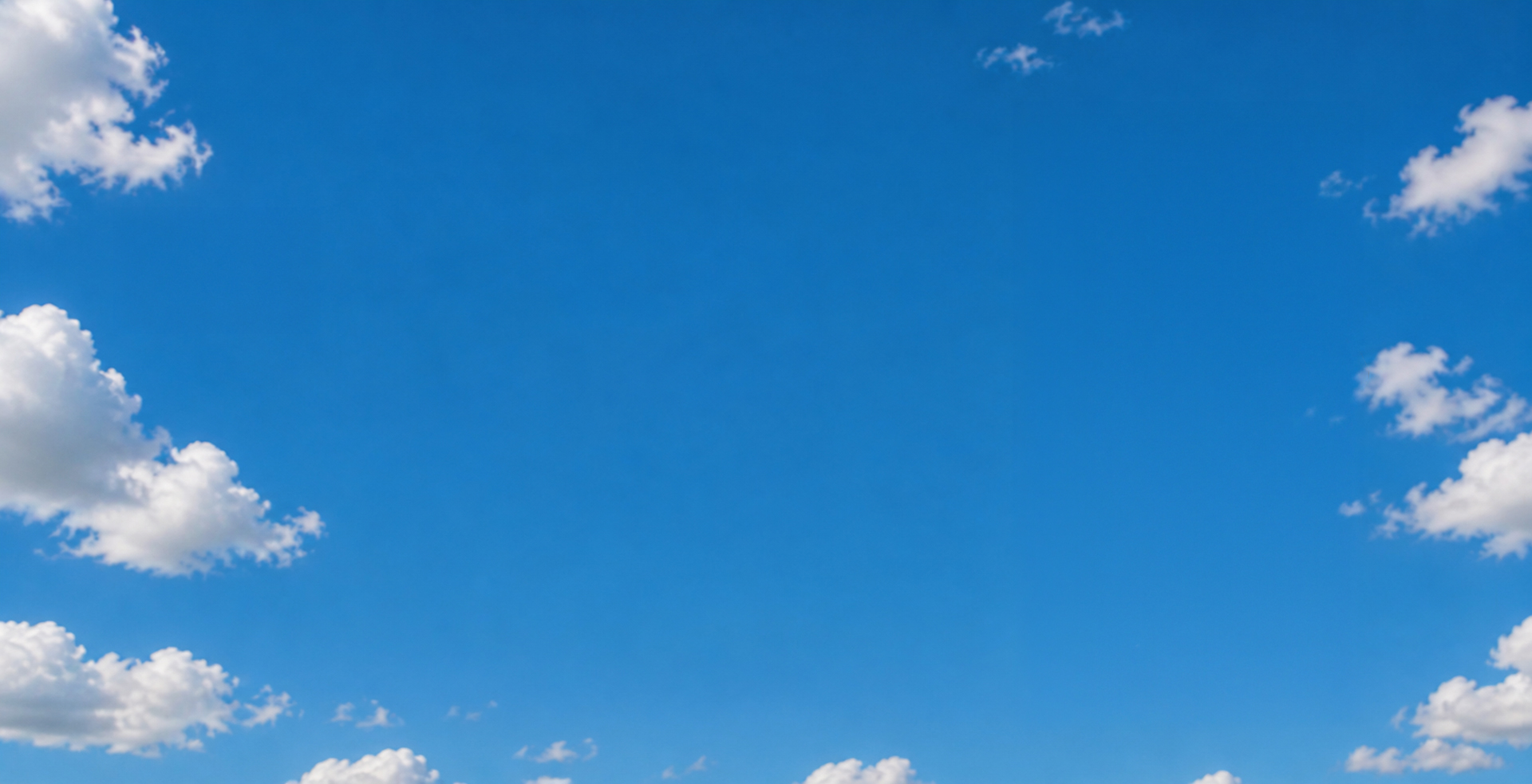 Bright blue sky with scattered white fluffy clouds.