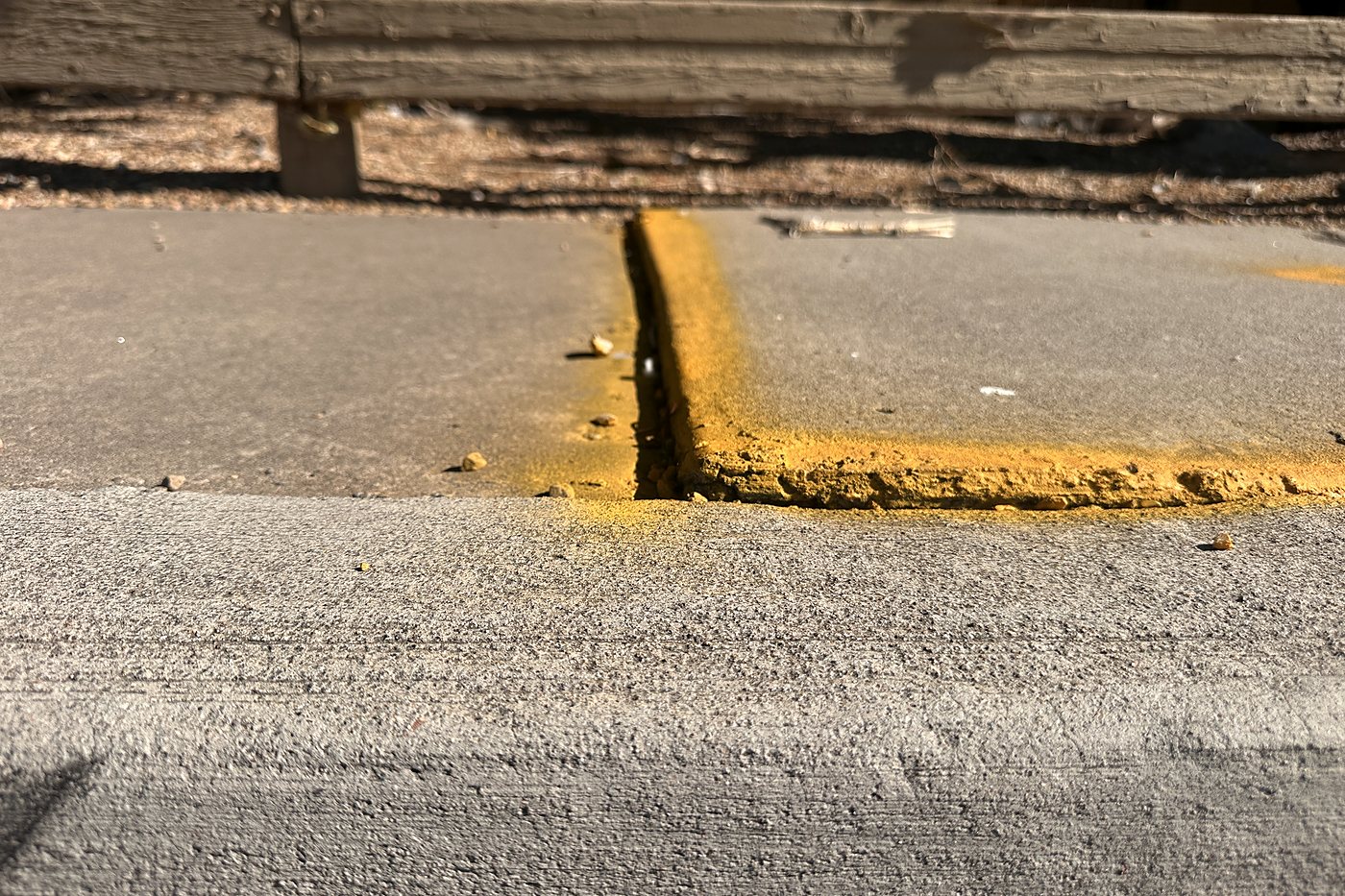 Low-angle close-up of a raised concrete sidewalk trip hazard
