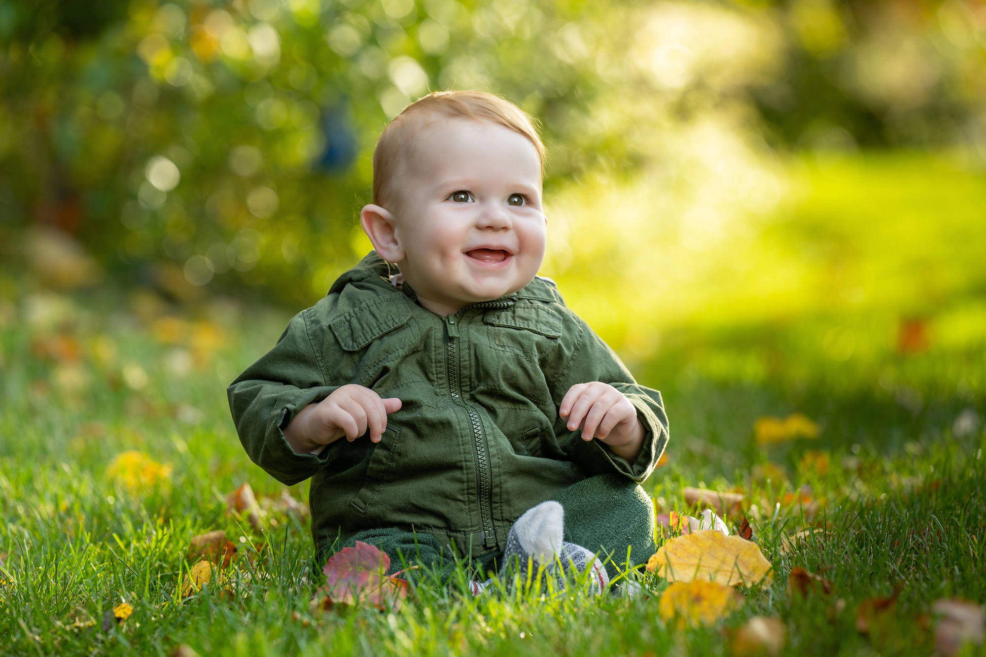 Baby sitting in the grass among fallen yellow leaves - fall family session in Nova Scotia