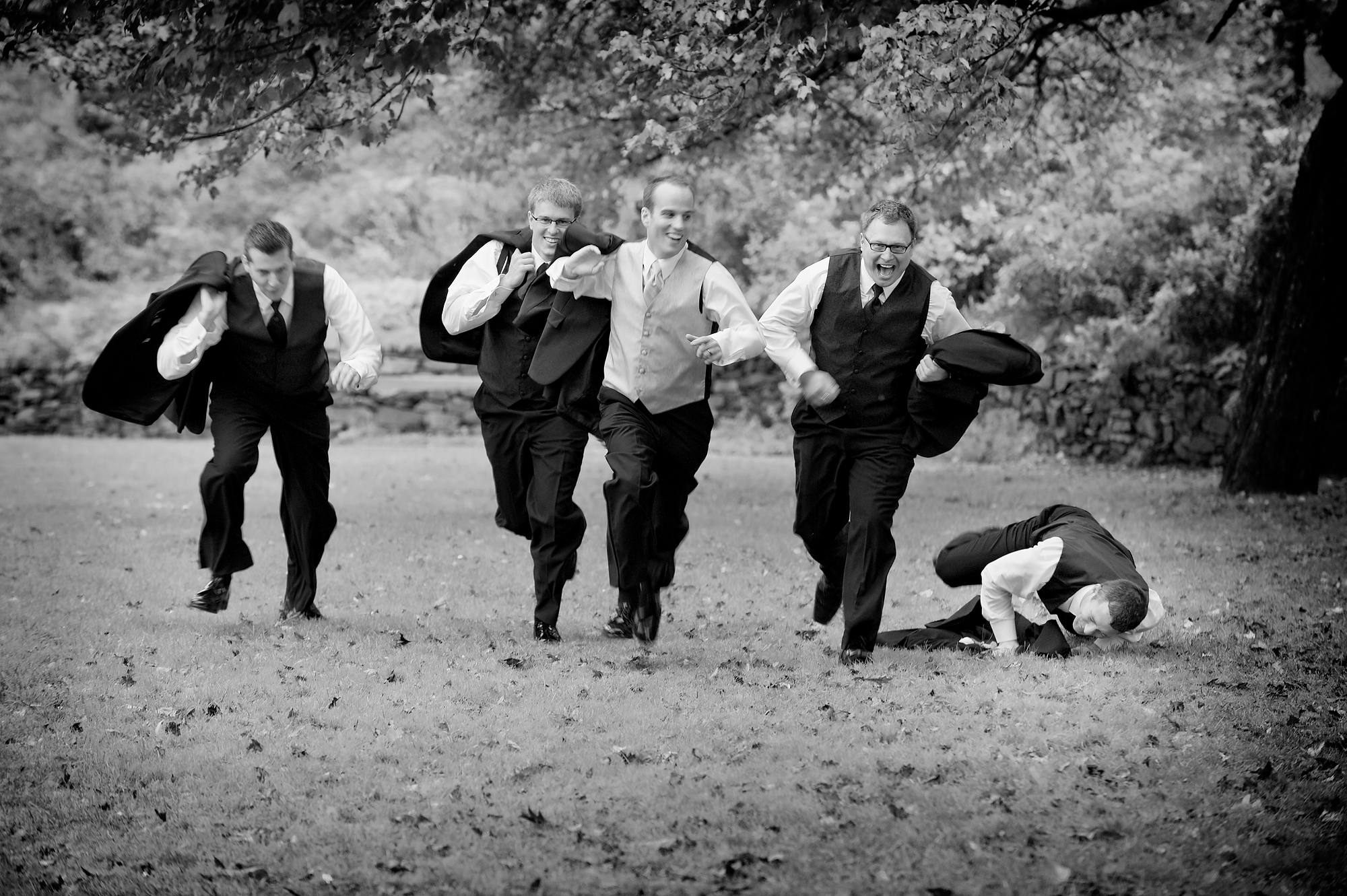 Groomsmen sprinting across the lawn at Leighton Dillman Park, Dartmouth, one down laughing
