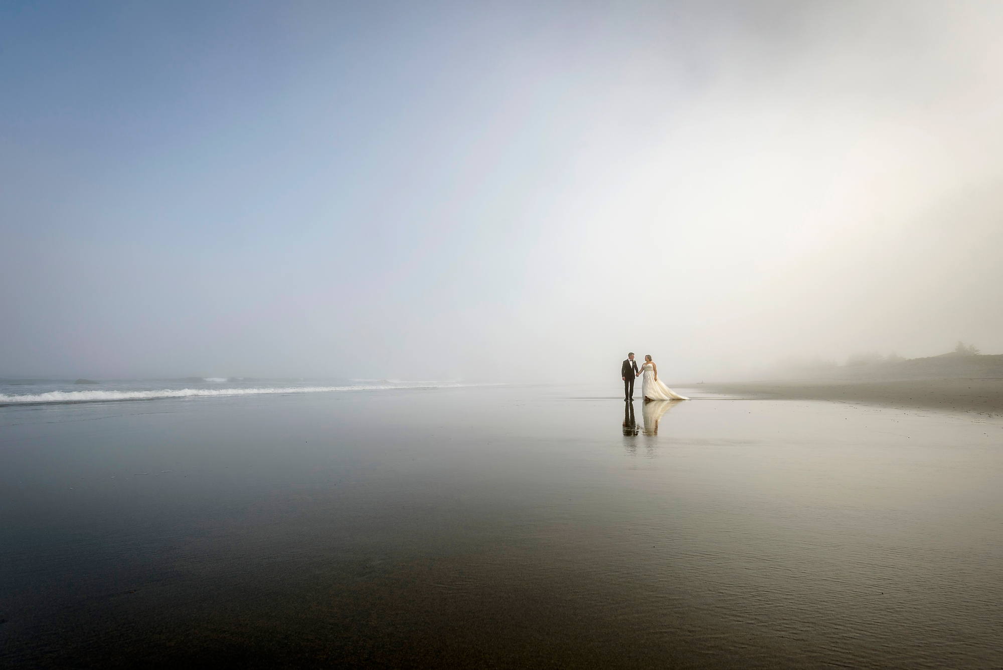 Bride and groom on the wet sand in the fog at White Point Beach, Nova Scotia wedding