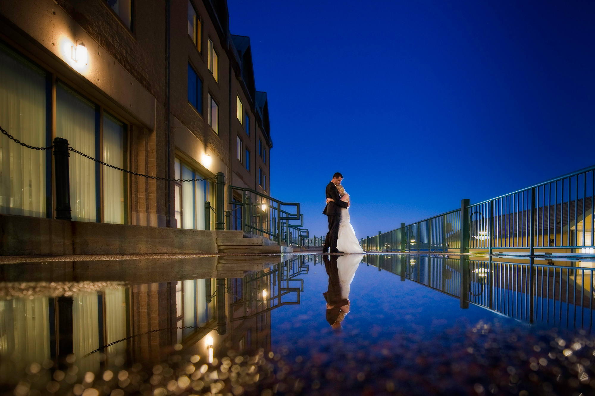 Bride and groom embracing at blue hour on the Halifax waterfront, reflected in a puddle