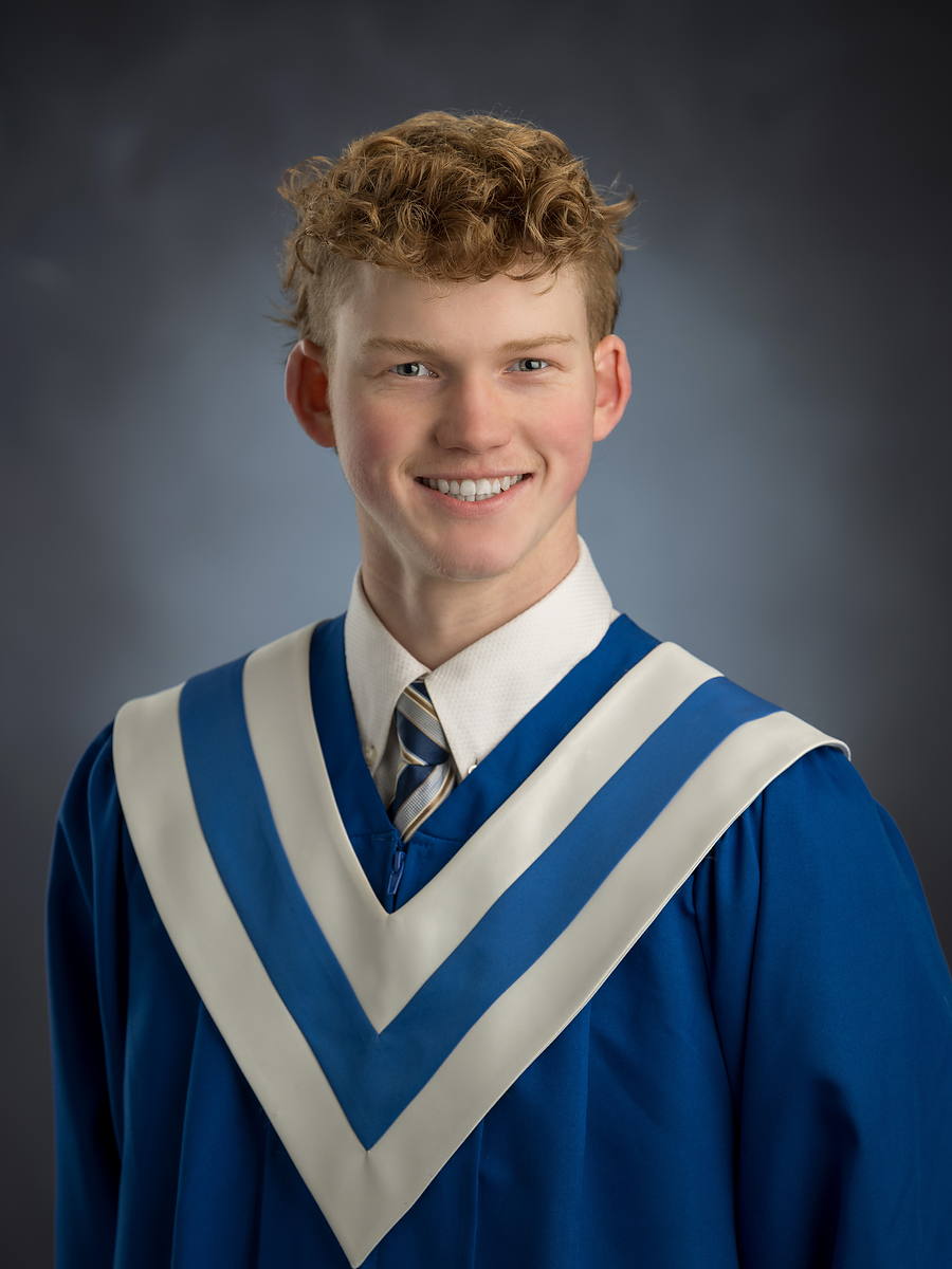 Smiling grad in a royal blue gown with a white sash, Halifax high school grad photo