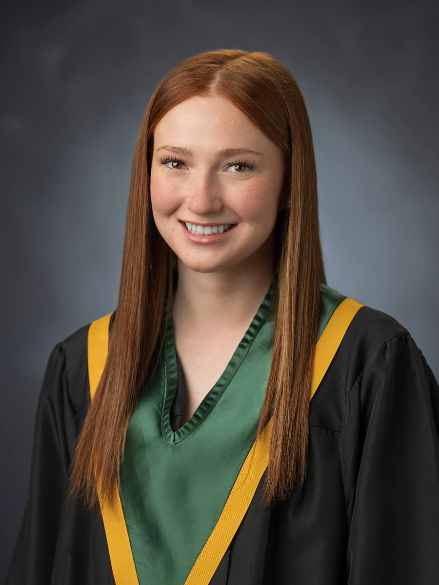 Grad with long red hair in a black gown with a green and gold sash, Halifax grad portrait