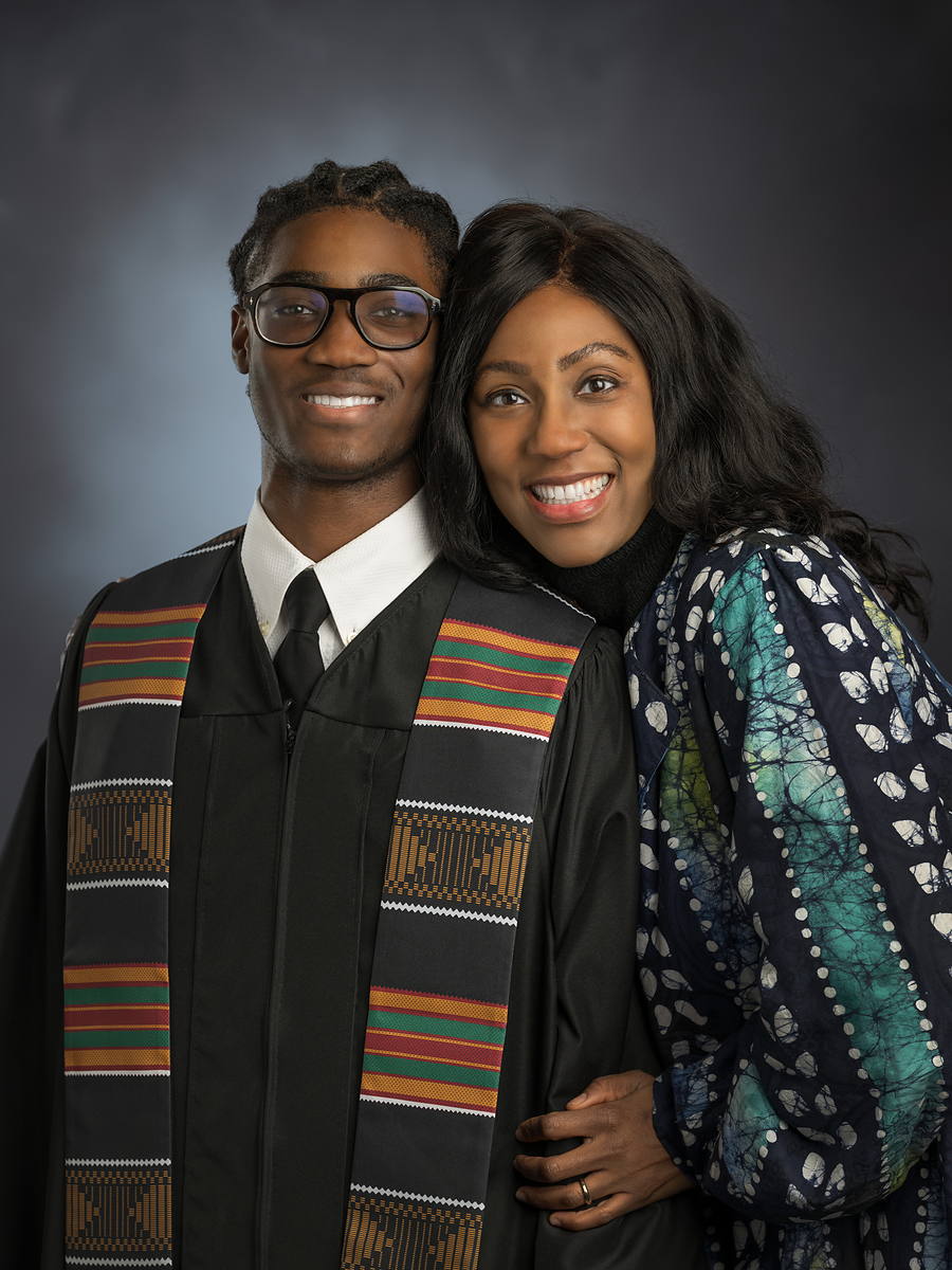 Grad in a black gown and kente stole with his mother beside him, Halifax grad photo