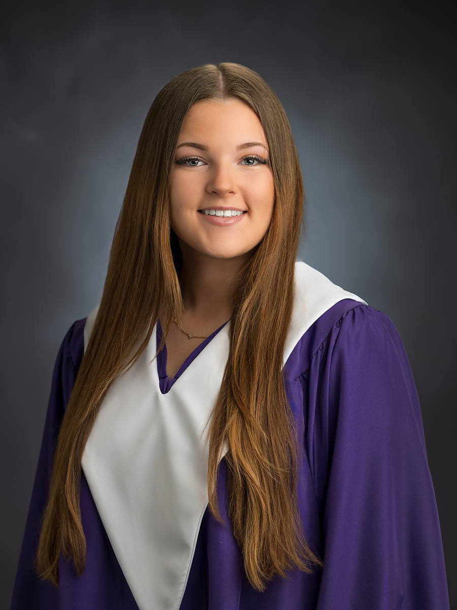 Grad in a purple gown with a white stole, studio graduation portrait in Halifax