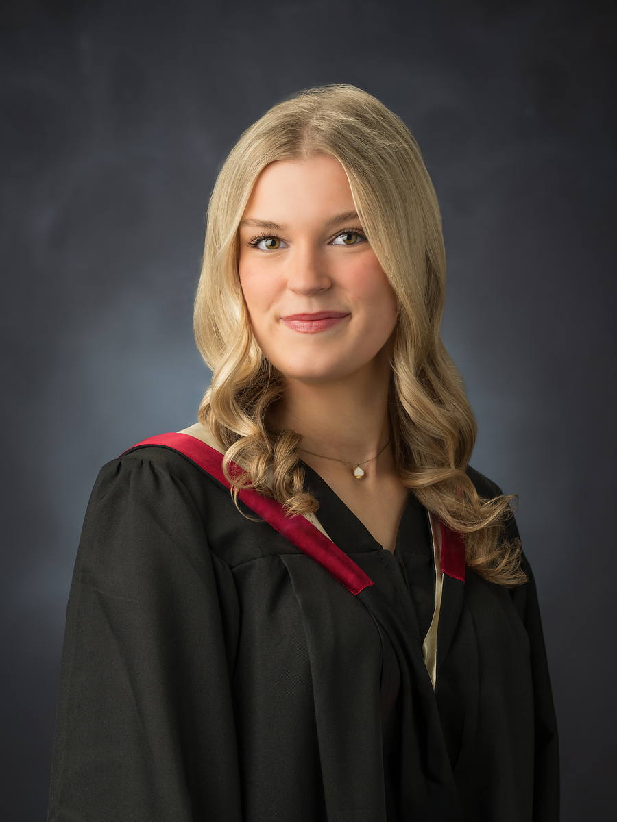 Halifax West High grad in a black gown with a red V-sash, studio graduation portrait