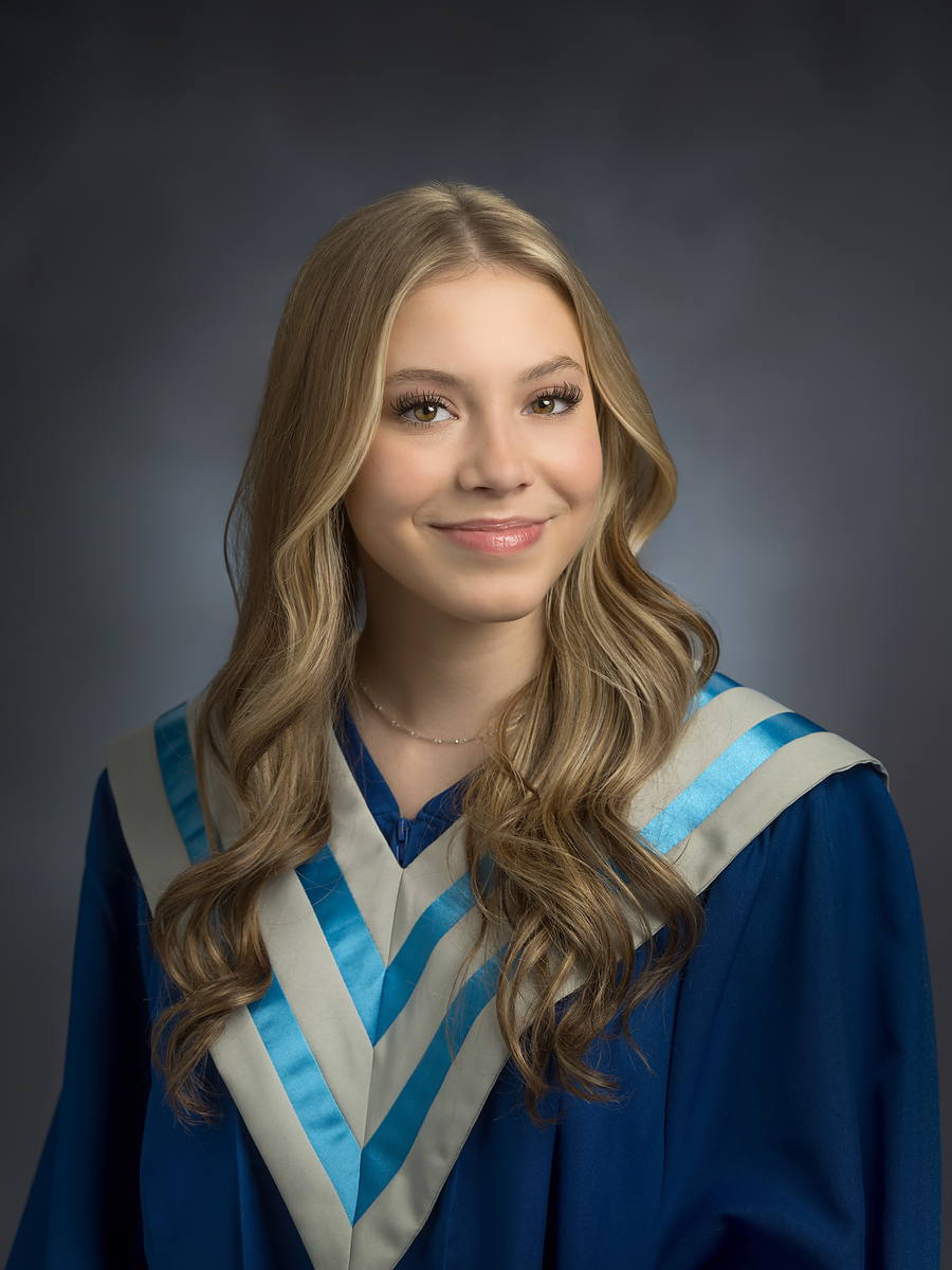 Lockview High grad in a blue gown with a white and light blue sash, studio grad portrait