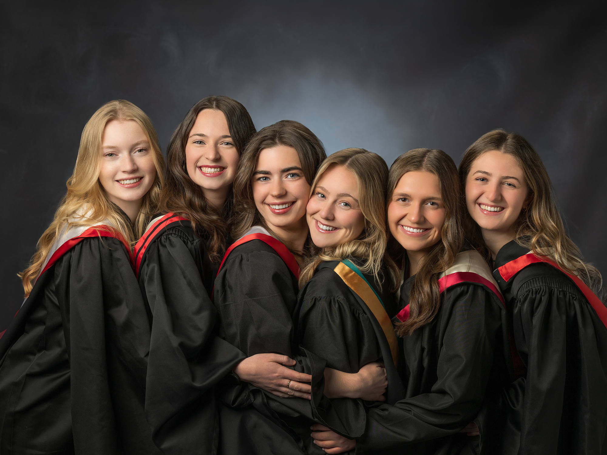 Six friends in grad gowns with red trim laughing together, Grad Plus session in Halifax