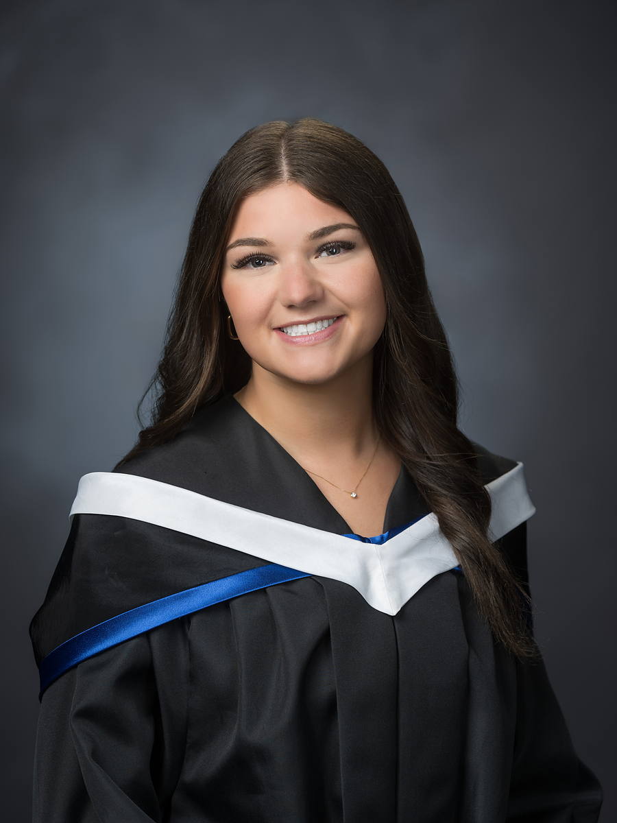 Grad with long dark hair in a black gown with a white and royal blue sash, Halifax grad portrait