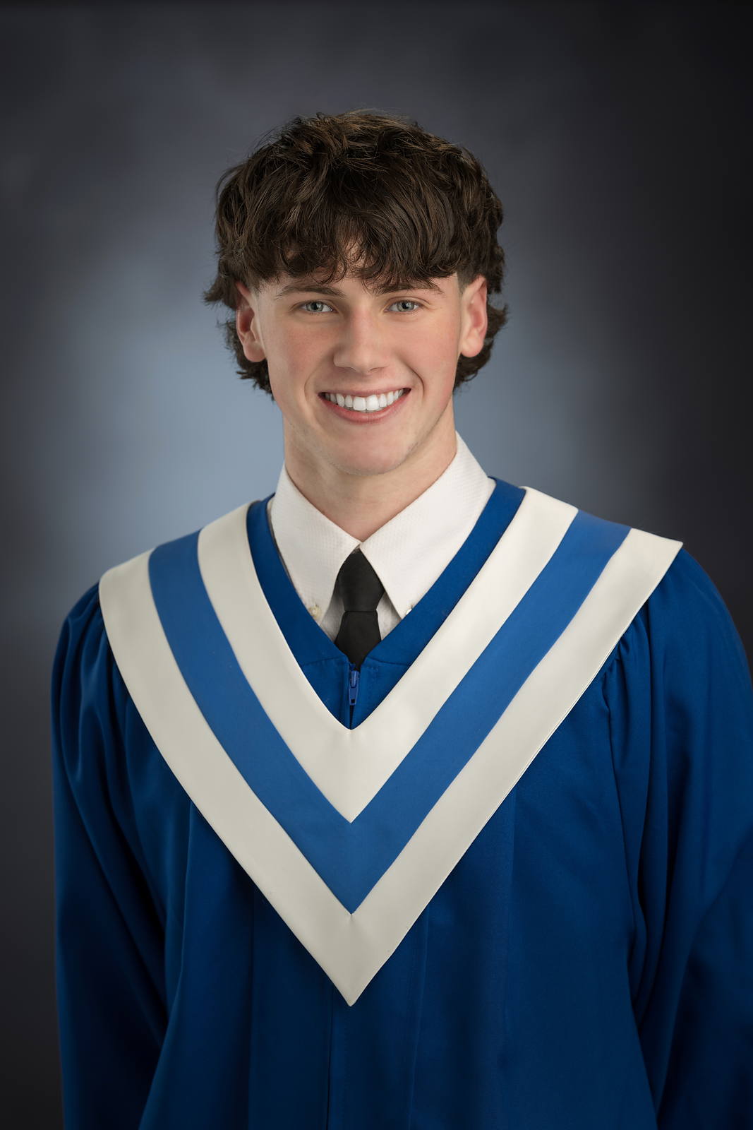 Smiling Lockview High grad in a blue gown with a white and light blue sash, studio portrait in Halifax