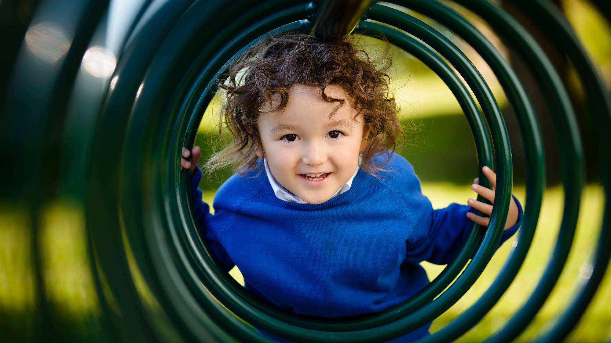 Child peeking through playground equipment in a Halifax park