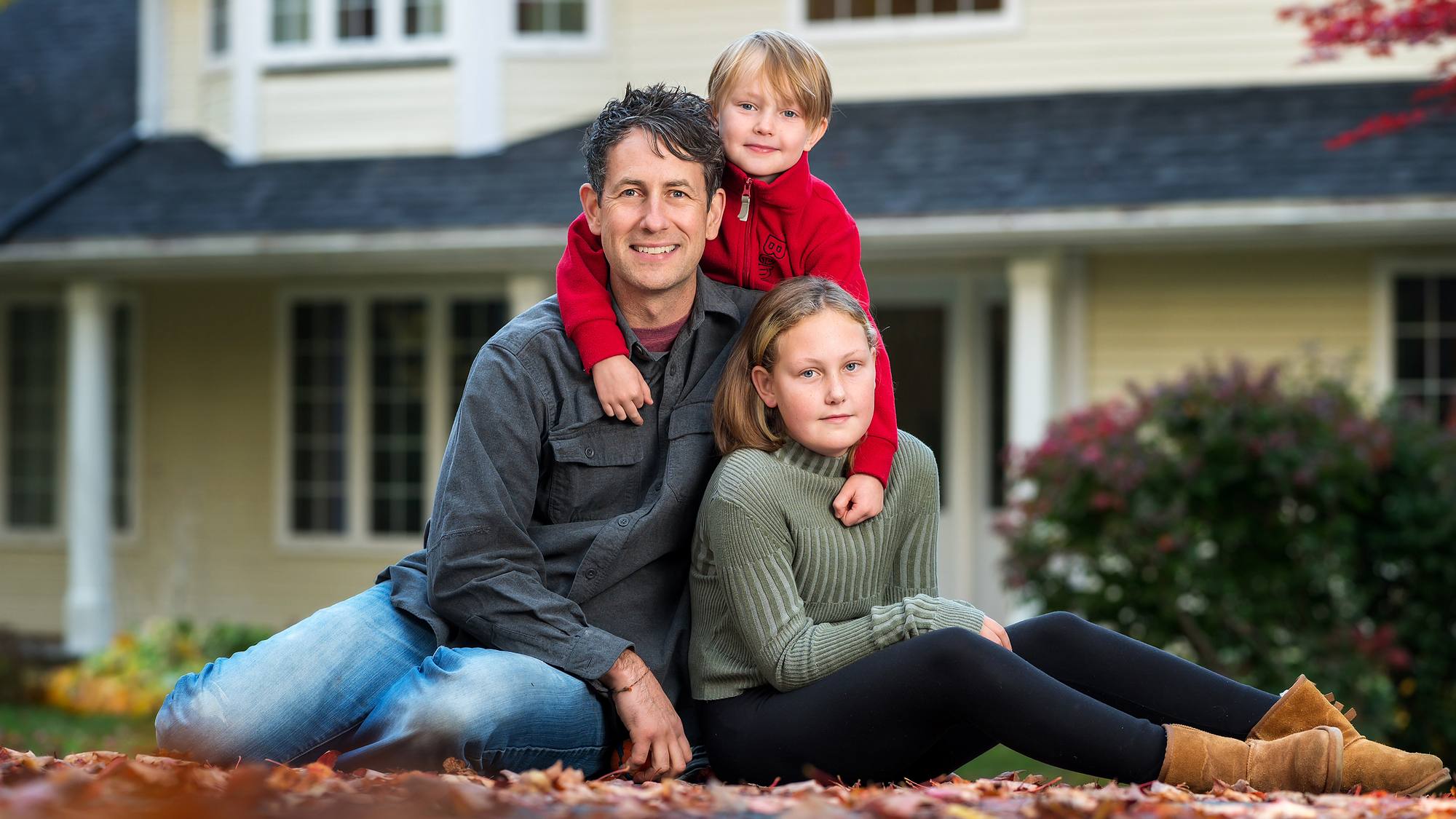 Fall family picture of dad and his kids in front of the family home