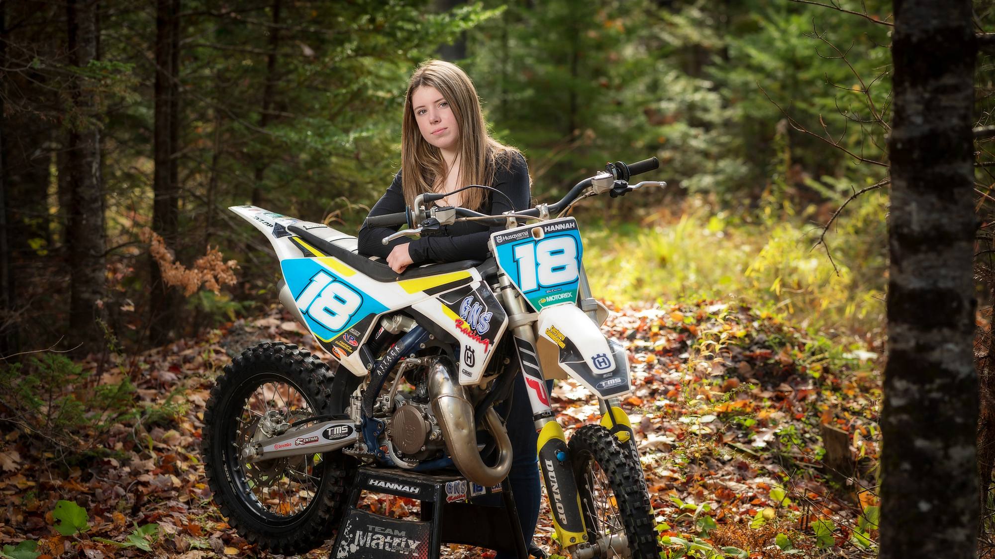 Teen with her dirt bike in a leaf-covered wood - fall family session in Nova Scotia