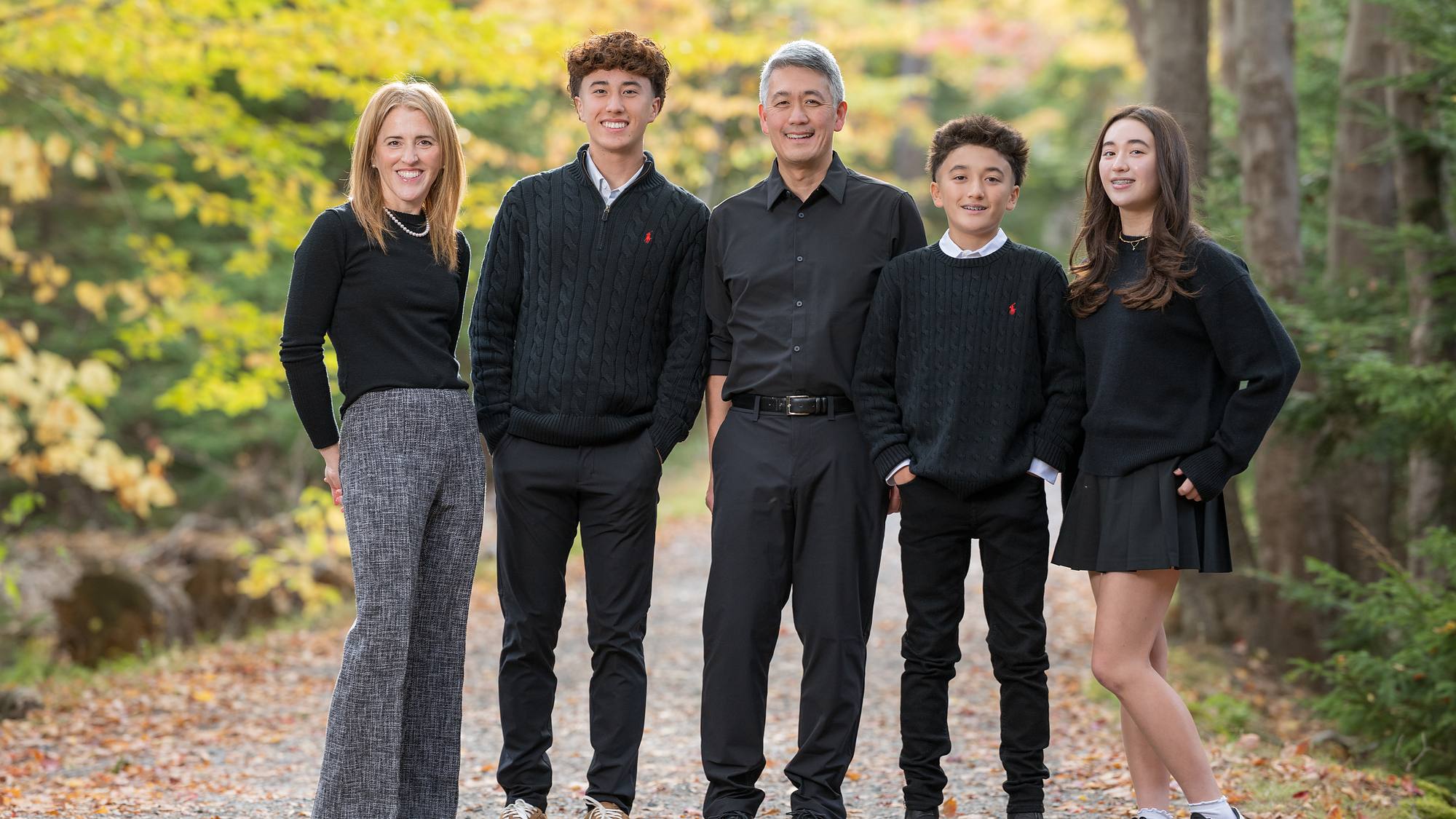 Family of five in black on a leaf-covered lane with autumn colour - fall family session