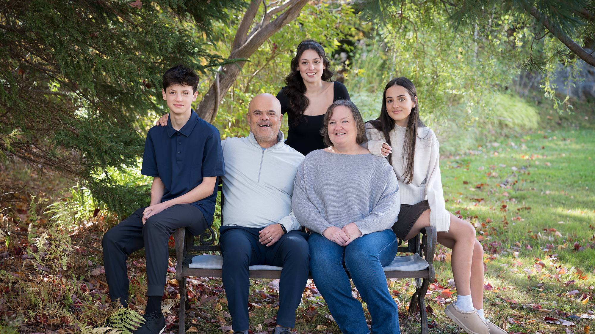 Family of five on a garden bench among fallen leaves - fall family session in Nova Scotia
