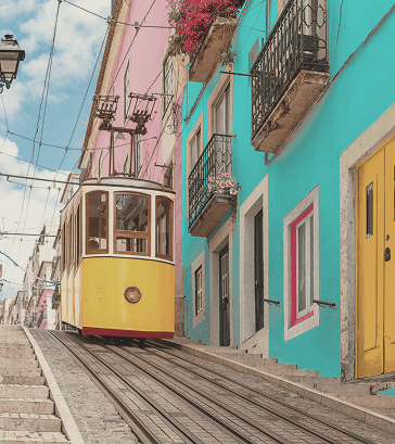 Yellow tram ascending a steep street lined with colorful buildings and balconies with flowers.