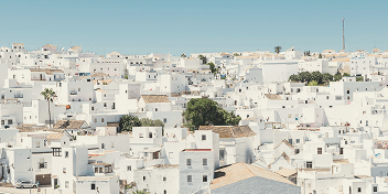 A dense cluster of white buildings with flat roofs under a clear blue sky in a Mediterranean town.