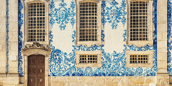 Facade with ornate blue floral tile patterns surrounding tall windows and a wooden door.