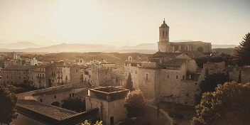 Sunset view over historic buildings and a church tower in a Catalonian town.