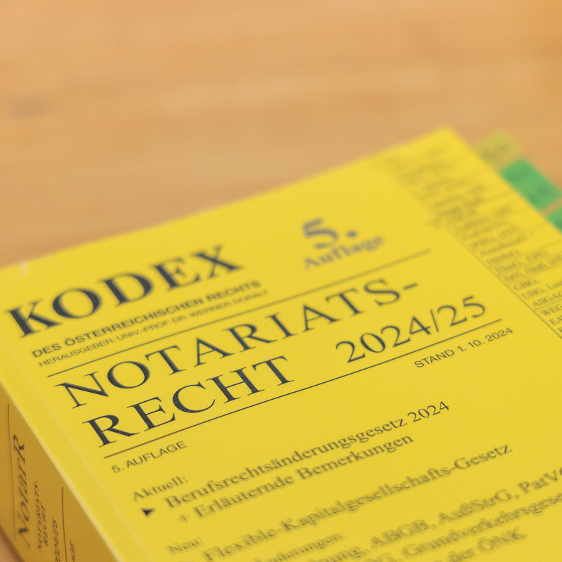 Nahaufnahme des Buches "Kodex Notariatsrecht 2024/25", 5. Auflage, Stand 1.10.2024, auf einem Holztisch im Notariat Mayrhofer.