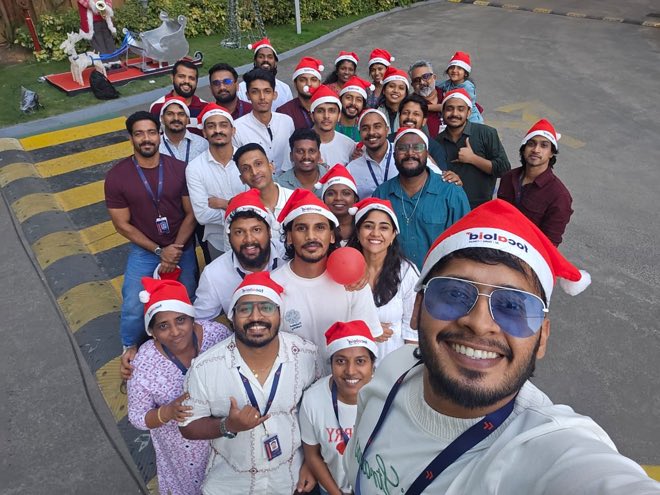 Colleagues in Santa hats gathered for a group selfie outside the office