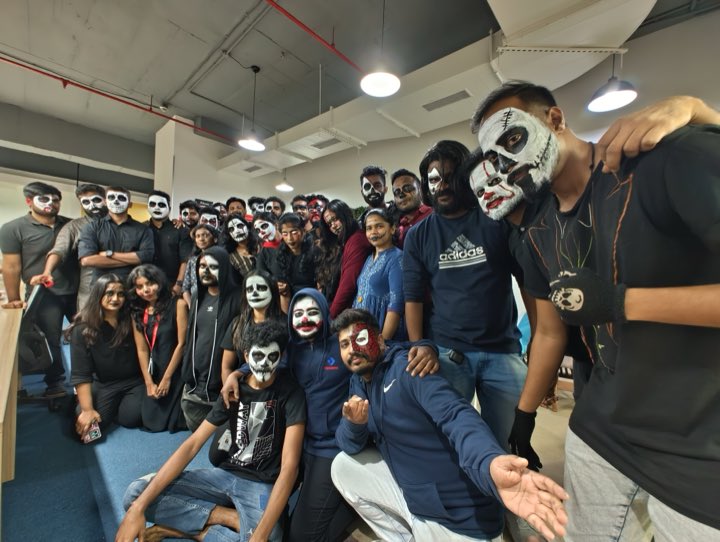 A large group of colleagues in Halloween face paint and black outfits