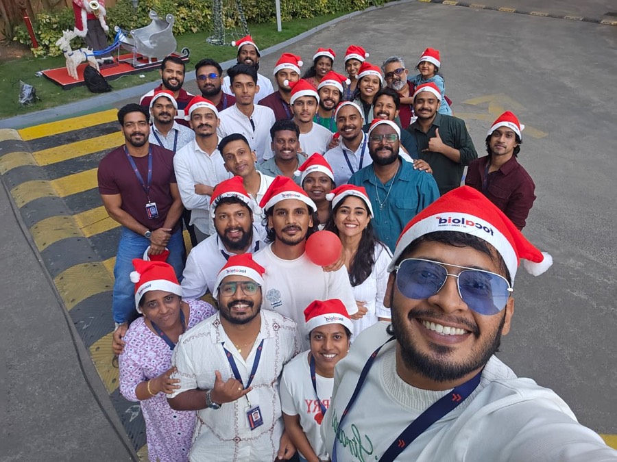 Colleagues in Santa hats packed into a group selfie in the office driveway