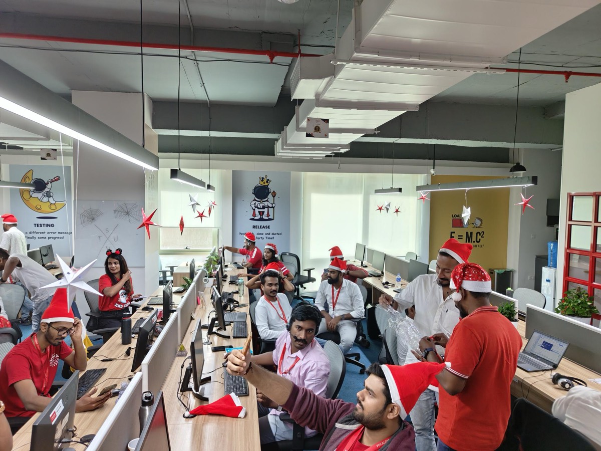 The open-plan office decorated with paper stars, with colleagues in Santa hats at their desks