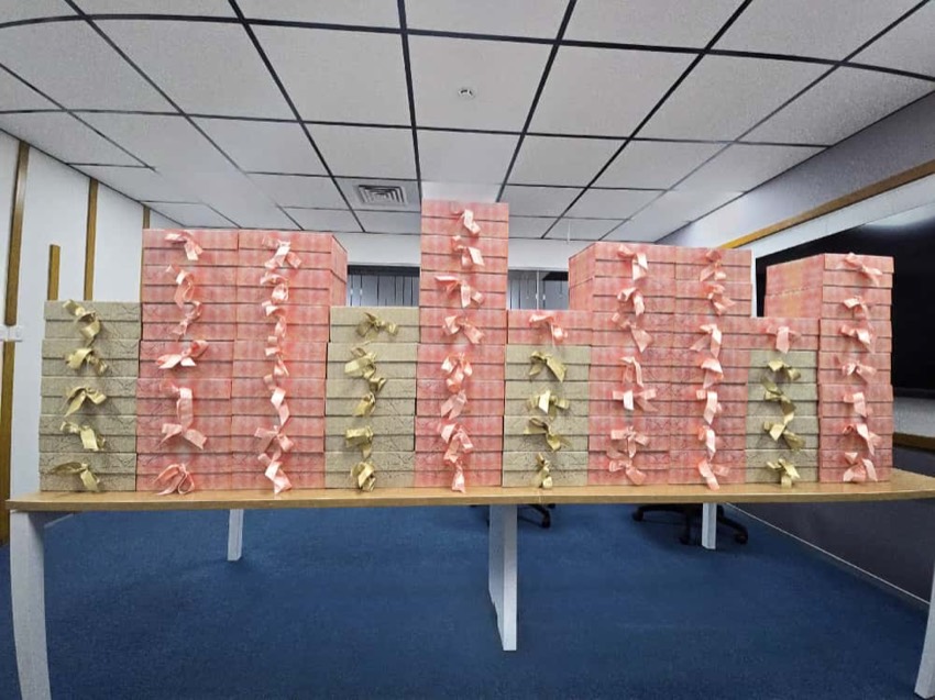 Dozens of ribboned gift hampers stacked in rows along a long office desk