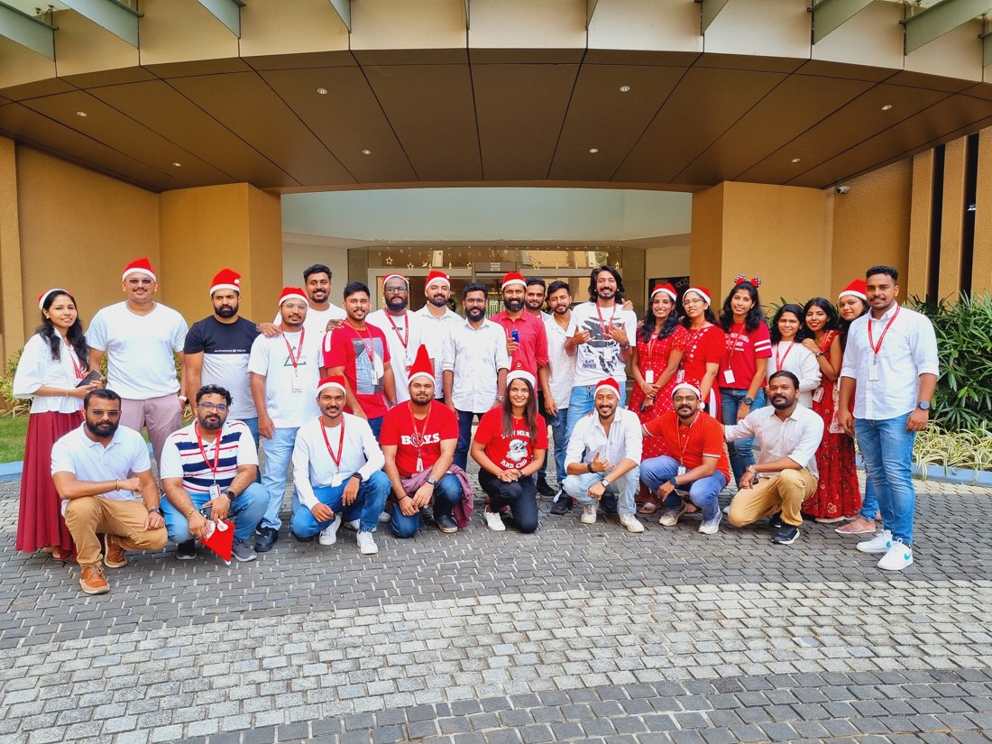 A large group photograph of the team in Santa hats and red and white clothing outside the office