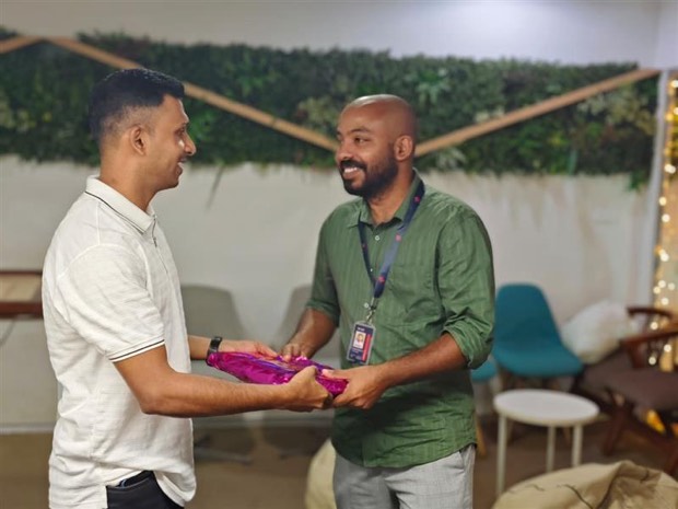 Two colleagues smiling as one hands over a wrapped gift