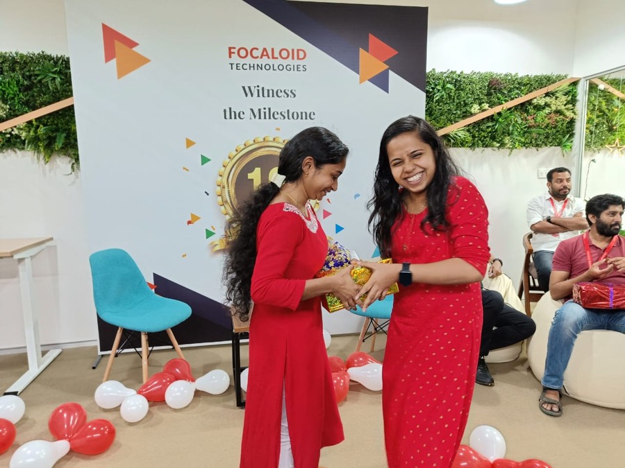 Two colleagues in front of a Focaloid Technologies backdrop reading Witness the Milestone with a gold laurel badge containing the number ten