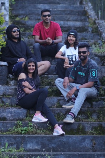 Five colleagues sitting on mossy stone steps on a hillside