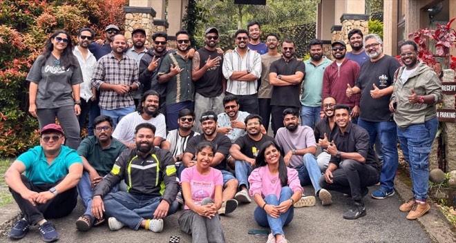 A large group of colleagues posing outdoors on a garden path during an offsite