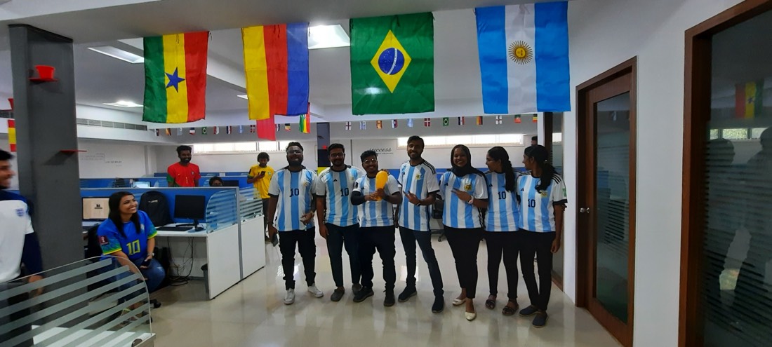 Colleagues in Argentina jerseys posing under the strung flags in the office