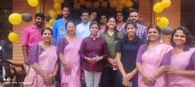 Around a dozen Focaloid colleagues standing together under yellow and black balloons outside a decorated building
