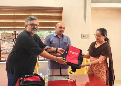 A Focaloid colleague handing a backpack across a table to a member of the school staff