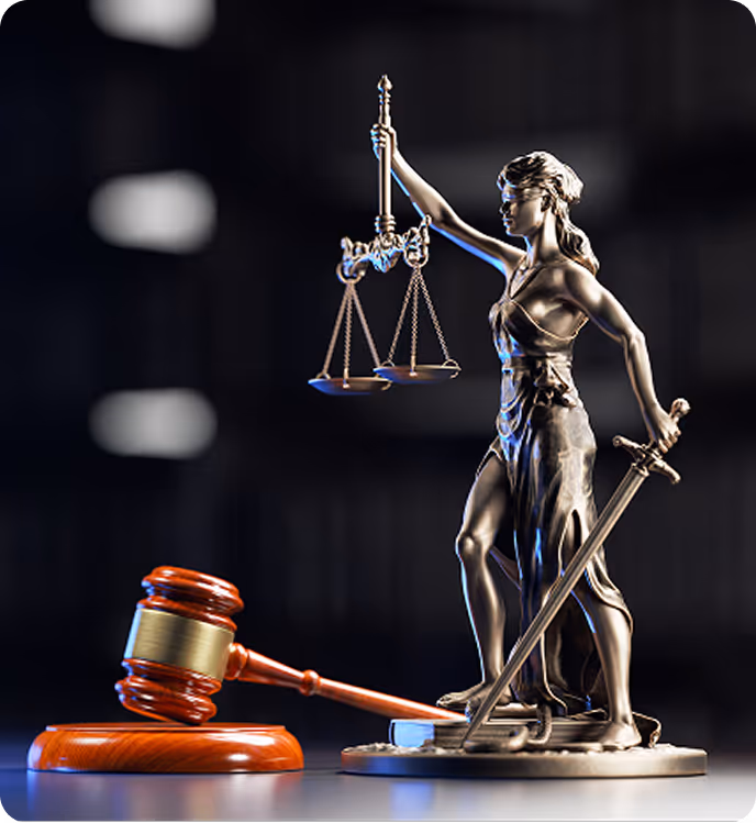 Bronze statue of Lady Justice holding scales and sword beside a wooden judge’s gavel on a dark background.
