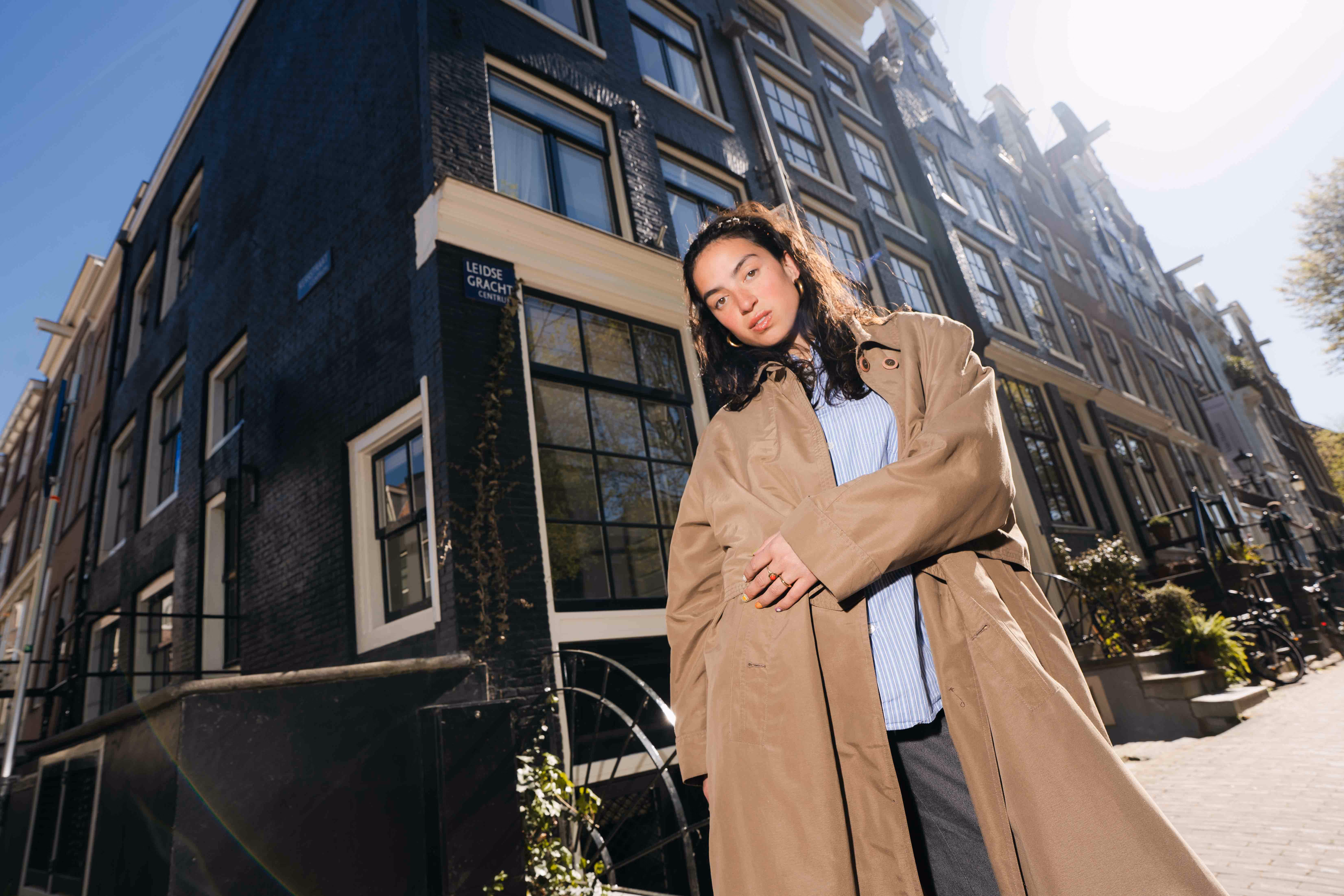 Studente in lange jas in een Amsterdamse straat