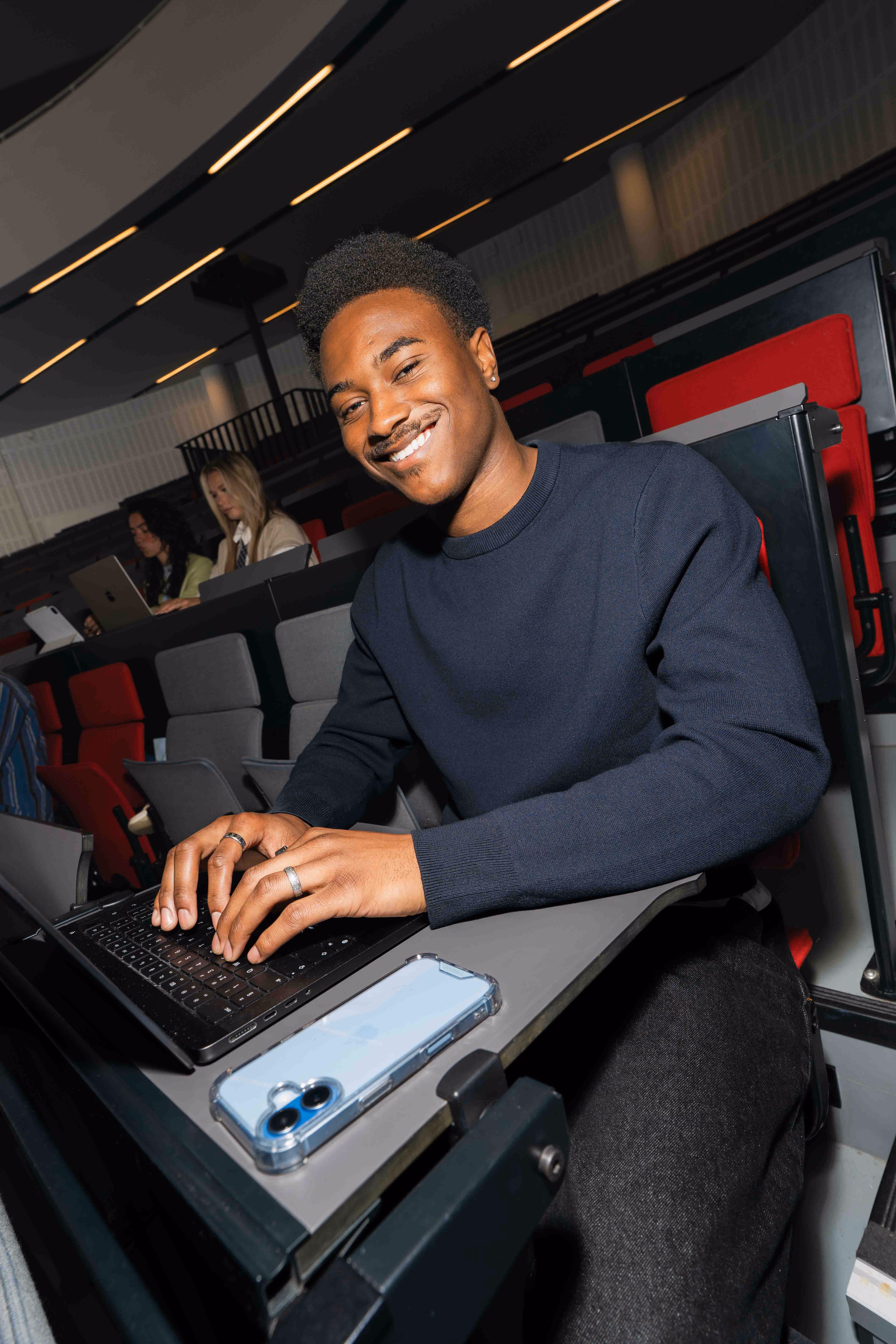 Student werkt op een laptop in een collegezaal